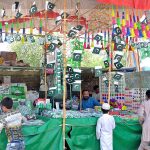 Vendors displaying national flags and other related stuff to attract customers at his roadside set up in connection with upcoming Independence Day celebrations