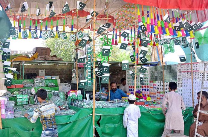 Vendors displaying national flags and other related stuff to attract customers at his roadside set up in connection with upcoming Independence Day celebrations