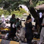 People purchasing shoes from the roadside vendors at Abpara market