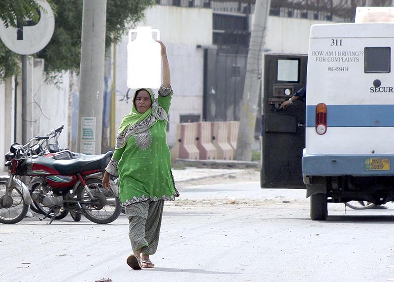 A woman on the way back carrying water cane on her head after filling from a filtration plant.