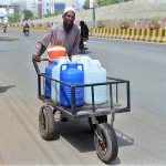 A person pushing his hand cart loaded with clean drinking water supply to Market