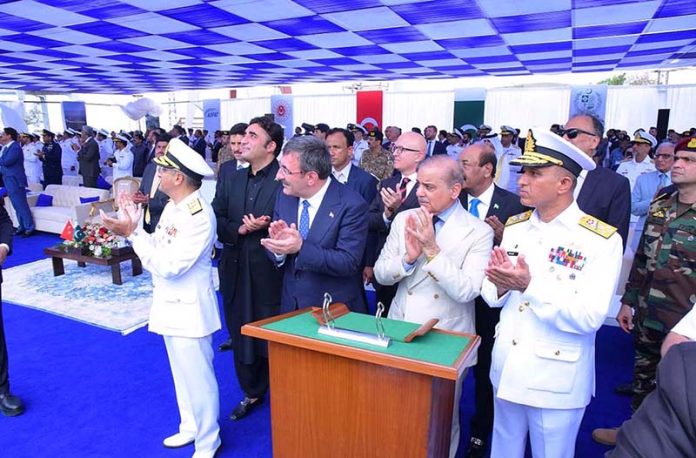 Prime Minister Muhammad Shehbaz Sharif, Türkiye's Vice President Cevdet Yilmaz and Chief of Naval Staff Admiral Muhammad Amjad Khan Niazi applaud after cutting a rope to launch Pakistan's 4th MILGEM Class Corvette