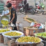 A vendor busy displaying lemons to attract customers at his roadside setup.