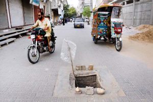 A significant group of individuals is traveling on tricycle carts along Railway Station Road
