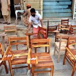 A worker busy polish on the wood chairs at his workplace