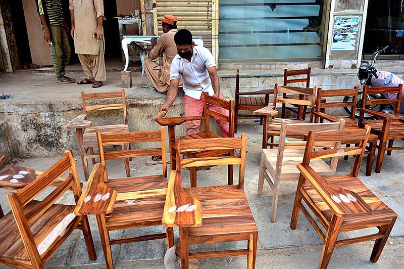 A worker busy polish on the wood chairs at his workplace