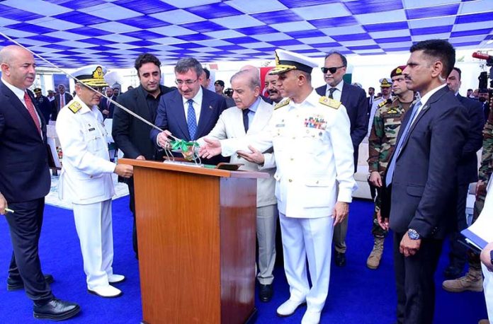 Prime Minister Muhammad Shehbaz Sharif, Türkiye's Vice President Cevdet Yilmaz and Chief of Naval Staff Admiral Muhammad Amjad Khan Niazi applaud after cutting a rope to launch Pakistan's 4th MILGEM Class Corvette