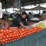 A vendor selling vegetables on his stall at Sunday bazaar Abpara Market