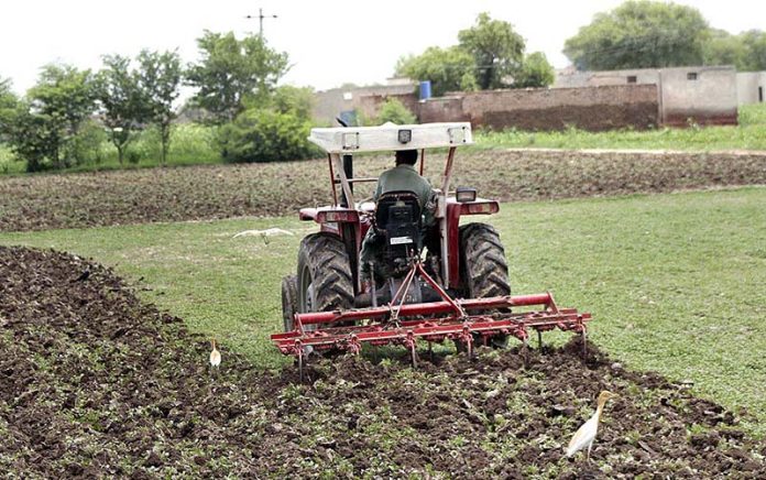Farmer is busy preparing his farm field with the help of a tractor