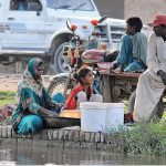 A gypsy woman washing clothes while sitting on the bank of the Canal