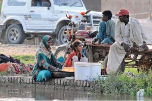 A gypsy woman washing clothes while sitting on the bank of the Canal