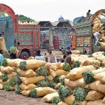 Labourers offloading sacks of vegetables from delivery truck at vegetable market