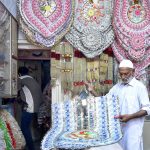 A shopkeeper making traditional currency notes garland used in wedding ceremonies