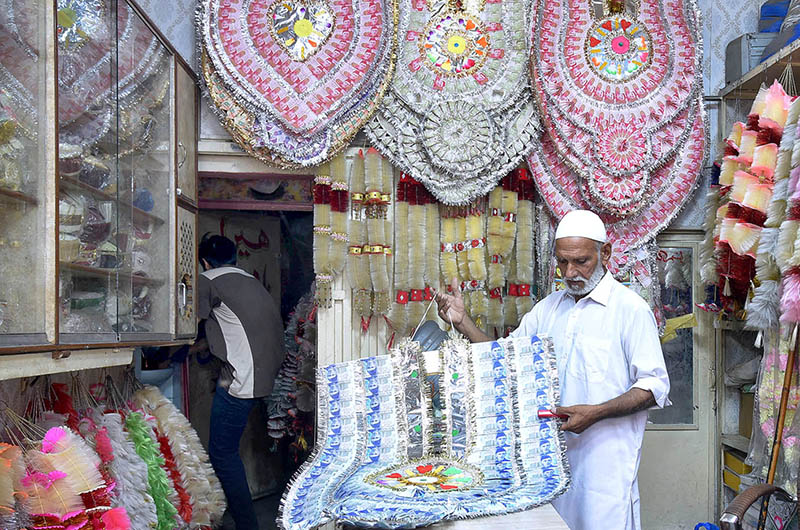 A shopkeeper making traditional currency notes garland used in wedding ceremonies