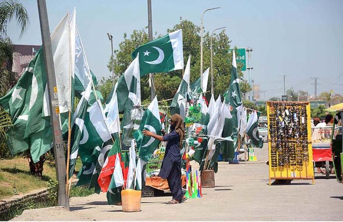Vendor displaying National flags to attract the customers as the nation starts preparations to celebrate Independence Day in befitting manners at Ring road