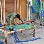Workers knitting a traditional bed (Charpai) at his workplace.
