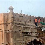 Labourers busy in restoration work on the wall of historical Shahi Qila