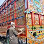 A truck painting artist preparing a body of a delivery truck at his workplace