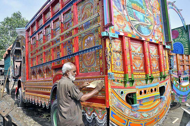 A truck painting artist preparing a body of a delivery truck at his workplace