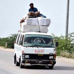 A passenger traveling in a risky way on the rooftop of a van at Bypass Road may cause any mishap and needs the attention of concerned authorities