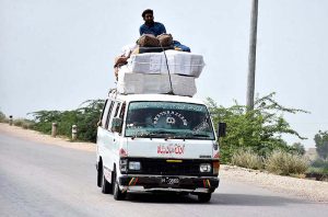 A passenger traveling in a risky way on the rooftop of a van at Bypass Road may cause any mishap and needs the attention of concerned authorities