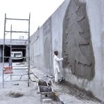 Skilled laborer busy in work to enhance the beauty of underpass wall at 7th Avenue during development work in Federal Capital