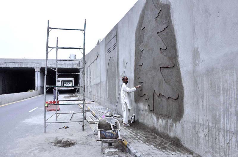 Skilled laborer busy in work to enhance the beauty of underpass wall at 7th Avenue during development work in Federal Capital