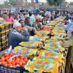 A vendor displaying tomatoes during an auction as shopkeepers participate in bidding at Vegetable Market