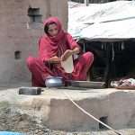 A woman making bread (roti) in a traditional oven (Tandoor) for her family members