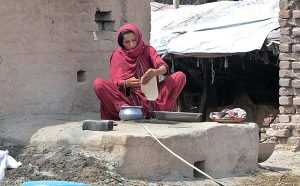 A woman making bread (roti) in a traditional oven (Tandoor) for her family members