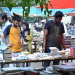 Book lovers selecting old books on a roadside stall in the city