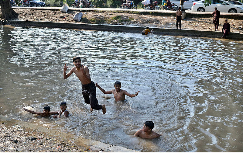 Youngsters jumping into canals to bathe in the rising heat and humid weather in the provincial capital
