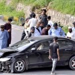 Security personnel and people gathered around a damaged car after an accident on Faisal Avenue near Zeropoint