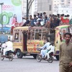 People dangerously travelling on a roof top of a minibus