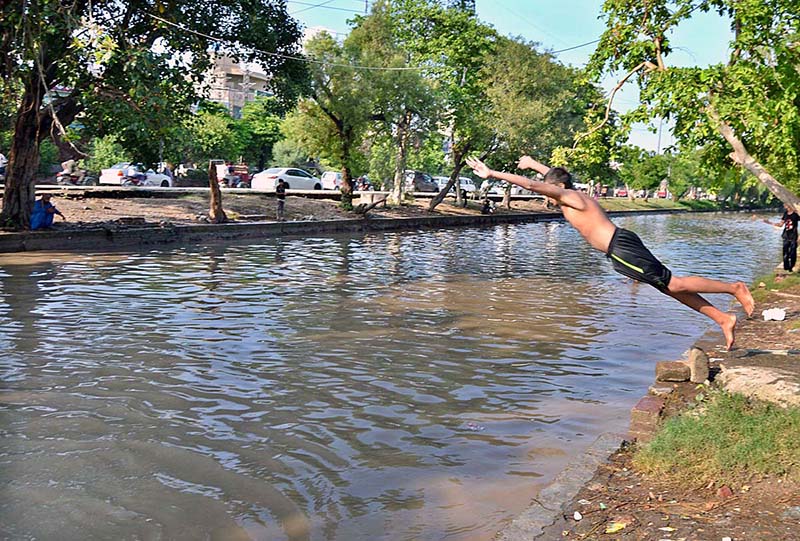 Youngsters diving into canal to bathe in the rising heat and humid weather in the city