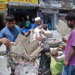 An elderly vendor selling hand fans to customers on his bicycle to earn livelihood in Provincial Capital