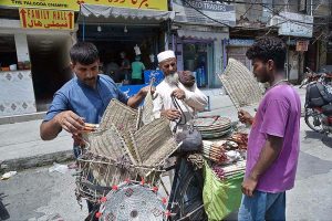 An elderly vendor selling hand fans to customers on his bicycle to earn livelihood in Provincial Capital