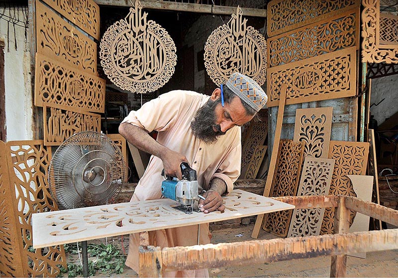 A carpenter busy in carving different designs on wooden sheet at his workplace
