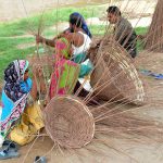 A gypsy family is preparing baskets with the dry branches of a tree at a roadside