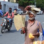 An elder vendor selling handmade hand fans while shuttling on GPO Road to earn for livelihood