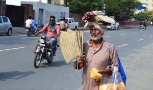 An elder vendor selling handmade hand fans while shuttling on GPO Road to earn for livelihood