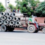 Workers transporting sewerage pipes to a project site