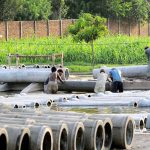 Labourers took out cement sewage pipes from water for drying purposes at their workplace