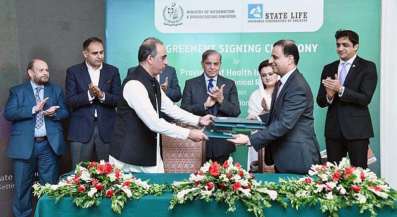 Principal Information Officer Mobashir Hassan and Executive Director of State Life Insurance Corporation Shahid Iqbal Baloch exchanging documents after signing an agreement for the provision of health insurance to working journalists and media workers associated with the media houses of Pakistan. Prime Minister Muhammad Shehbaz Sharif and Information Minister Ms Marriyum Aurangzeb witnessing the ceremony