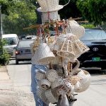 A vendor on his bicycle selling various handmade items in the city