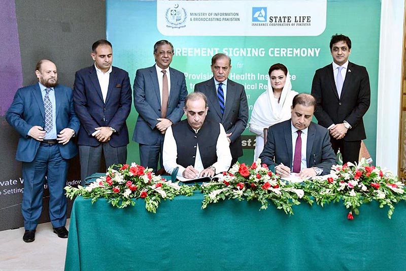 Principal Information Officer Mobashir Hassan and Executive Director of State Life Insurance Corporation Shahid Iqbal Baloch signing an agreement for the provision of health insurance to working journalists and media workers associated with the media houses of Pakistan. Prime Minister Muhammad Shehbaz Sharif and Information Minister Ms Marriyum Aurangzeb witnessing the ceremony