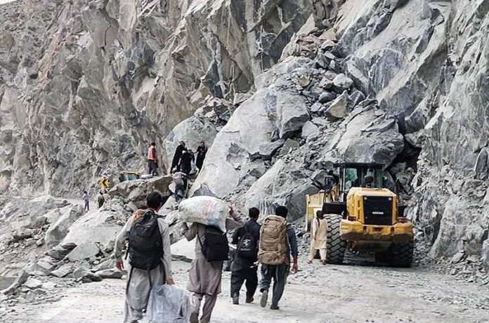 People crossing the blocked road on Juglot Skardu Road after land sliding near Rondu area