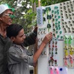 Vendors displaying national flags and other related stuff to attract customers at his roadside setup in connection with upcoming Independence Day celebrations in the city
