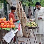 A man buys guavas outside the Victoria Hospital