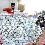 Vendor displaying tea cups to attract customers at roadside setup
